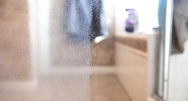 Restauration de vitre de douche avec traces d'eau calcaire qui ressemblent à des traces de pluie.